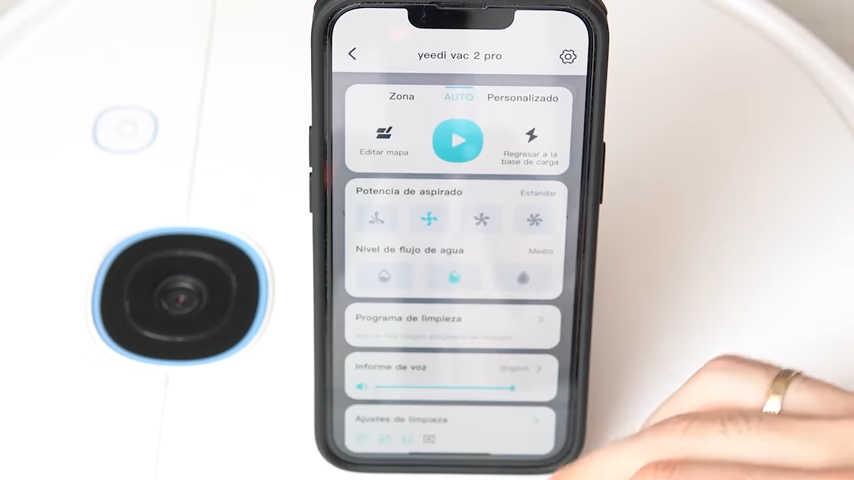Imagen de un teléfono móvil sobre el aspirador. En la pantalla del móvil se puede ver la aplicación del aspirador yeedi vac 2 pro abierta.