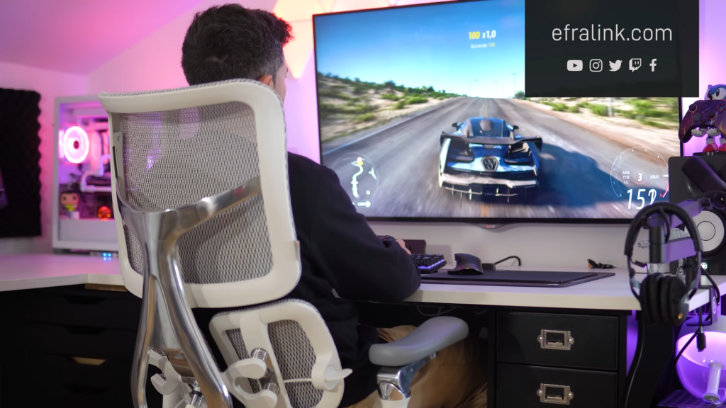 Aparece Efralink sentado en la silla Sihoo Doro S300 mientras que juega un videojuego de coches.